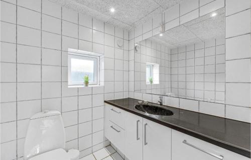 Baño de azulejos blancos con lavabo y aseo en Awesome Home In Ringkbing With Indoor Swimming Pool, en Klegod