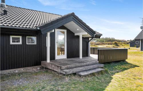 a small black house with a porch and a wooden ramp at Søndervig Ferieby in Ringkøbing