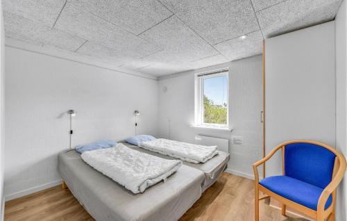 1 dormitorio con 2 camas y silla azul en Awesome Home In Ringkbing With Indoor Swimming Pool, en Klegod