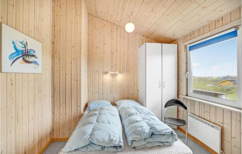 VestervigにあるBeautiful Home In Vestervig With 3 Bedrooms, Sauna And Wifiの窓と椅子が備わる客室のベッド1台分です。