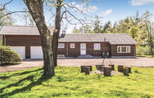 a log cabin with a tree in front of it at Five-Bedroom Holiday Home In Kibak in Ørbæk