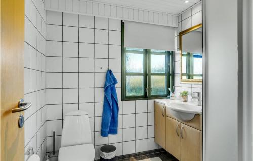 a white tiled bathroom with a toilet and a sink at 3 Bedroom Beautiful Home In Vestervig in Vestervig