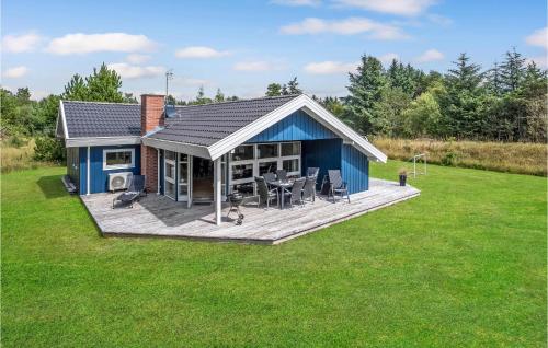 a blue house with a deck in a yard at Nice Home In Ringkøbing With Kitchen in Ringkøbing