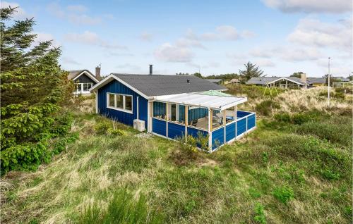 a blue house in the middle of a field at Holiday Home Fyrmarken Hvide Sande in Nørre Lyngvig