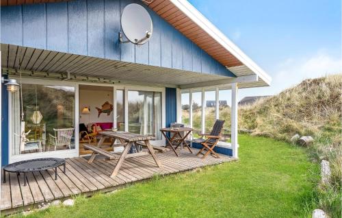 a blue house with a deck with a table and chairs at Holiday Home Svenstibakkevej Denm in Lild Strand