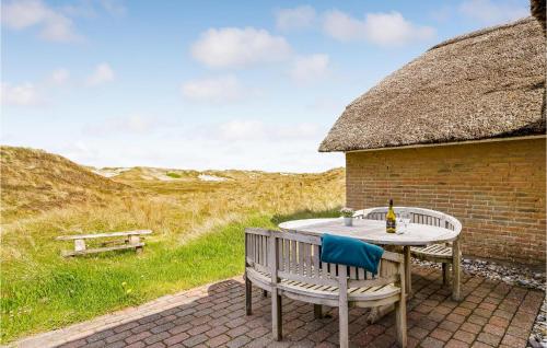 a table and chairs sitting on a patio with a thatch roof at Nice Home In Ringkøbing With Sauna in Søndervig