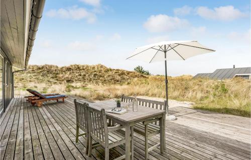 a table with an umbrella and chairs on a deck at Four-Bedroom Holiday Home In Ringkobing in Ringkøbing