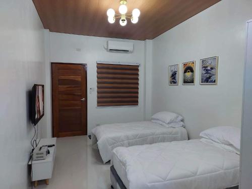 1 dormitorio con 2 camas, TV y ventana en FLB Apartelle Los Banos, en Los Baños