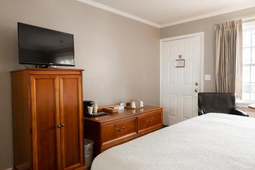 a bedroom with a bed and a television on a dresser at Admiral Motel in Lake George