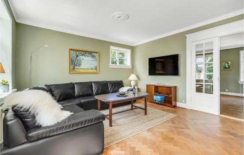 a living room with a black leather couch and a table at Anneksgaarden in Gadbjerg