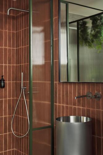 a bathroom with a tub and a shower with a mirror at The Newel Metaxourgeio in Athens