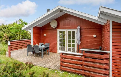 uma casa vermelha com uma mesa no convés em Nice Home In Frstrup With House Sea View em Lild Strand