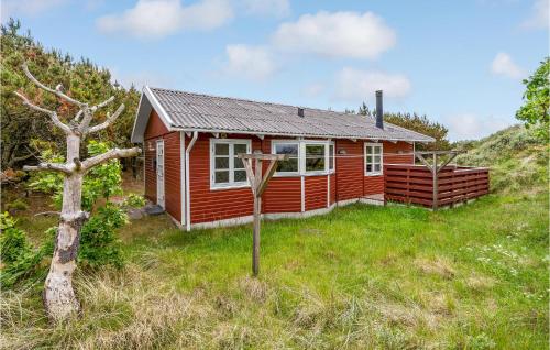 a red cabin in the middle of a grass field at Holiday Home Svenstibakkevej Denmark Ii in Lild Strand