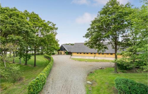 a driveway leading to a yellow house with trees at Rishøj in Hjarbæk