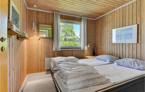 Cozy Home In Sydals With Kitchen في Skovby: غرفة نوم بسريرين في جدار خشبي