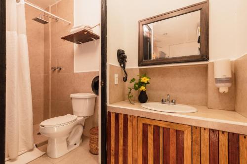 a bathroom with a toilet and a sink and a mirror at Che Playa Hostel & Bar Adults Only in Playa del Carmen