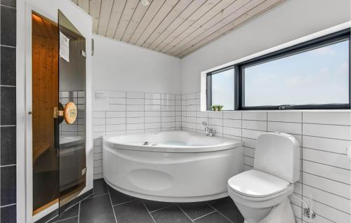 a bathroom with a tub and a toilet and a window at Amazing Home In Sydals With 3 Bedrooms, Sauna And Wifi in Skovby