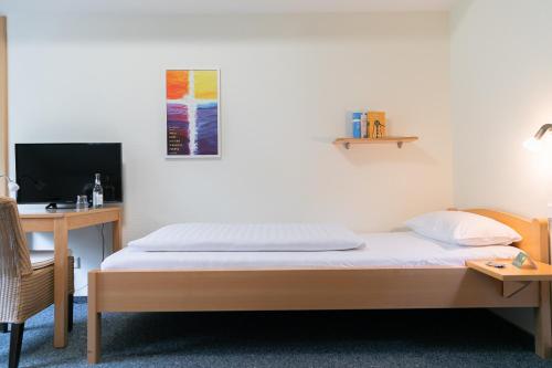 sypialnia z łóżkiem, biurkiem i telewizorem w obiekcie Gästehaus TABOR w mieście Marburg