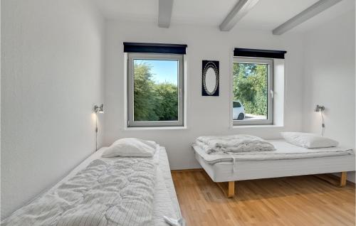 two beds in a white room with two windows at Holiday Home Grønmark in Høruphav