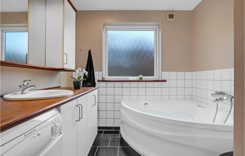 Baño blanco con bañera y lavamanos en Nice Home In Ebeltoft With Kitchen en Øksenmølle