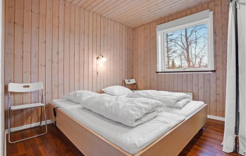 a bedroom with a bed with white sheets and a window at Nice Home In Ebeltoft With Kitchen in Øksenmølle
