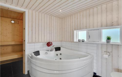 a large white tub in a bathroom with two windows at Amazing Home In Ejstrupholm With Kitchen in Krejbjerg
