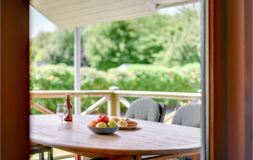 a wooden table with a bowl of fruit and a bottle of wine at Hønsehuset in Skovby
