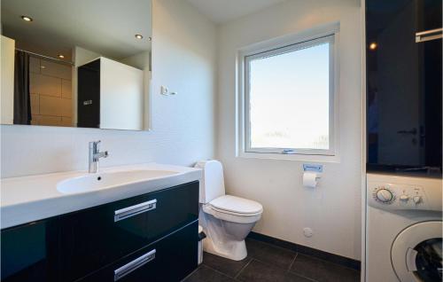 een badkamer met een wastafel, een toilet en een raam bij Lovely Home In Glesborg With House Sea View in Bønnerup Strand