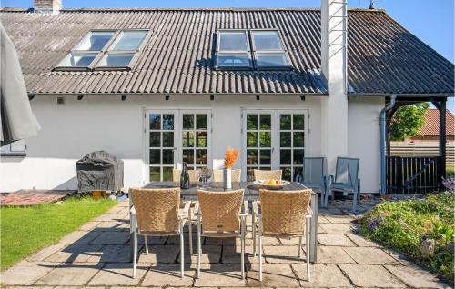 a patio with a table and chairs in front of a house at 4 Bedroom Awesome Home In Glesborg in Glesborg