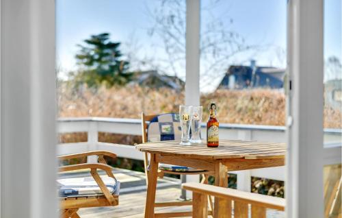a bottle of beer sitting on a wooden table on a porch at Gorgeous Home In Bjert With Wifi in Binderup Strand