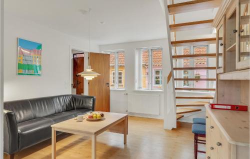 a living room with a black leather couch and a table at Stunning Home In Rudkøbing With Kitchen in Rudkøbing