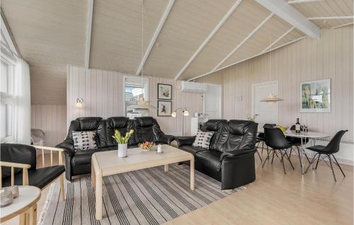 a living room with a black leather couch and a table at Three-Bedroom Holiday Home In Nordborg in Nordborg