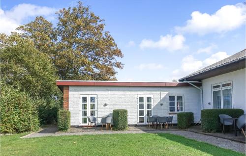 a white building with chairs and tables in a yard at Cozy Apartment In Allinge With Wifi in Allinge