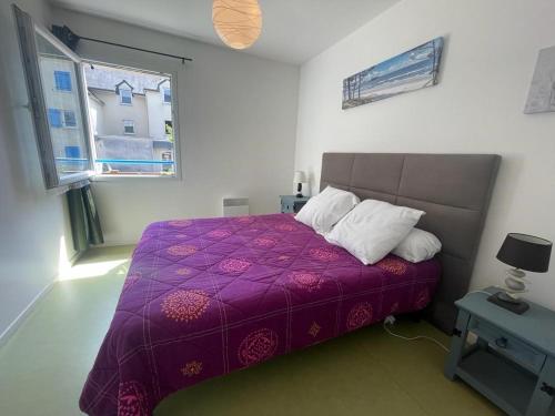 1 dormitorio con cama morada y ventana en Appartement à Belz proche de la mer, en Belz