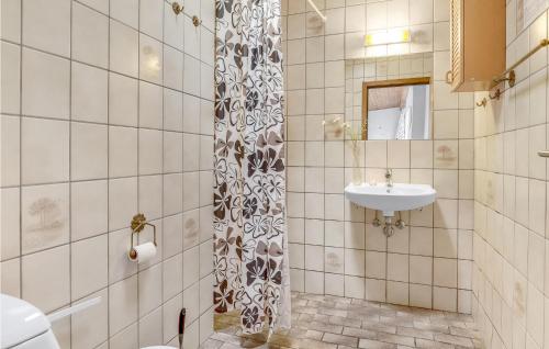 Baño de azulejos blancos con lavabo y espejo en Nice Apartment In Allinge With Kitchen, en Allinge