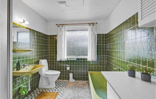 een badkamer met groene betegelde muren, een wastafel en een toilet bij 3 Bedroom Nice Home In Tranekr in Tranekær