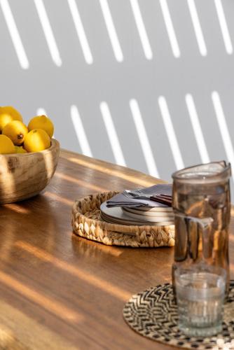 a wooden table with a glass of water and a bowl of fruit at Amalgam Homes Paros in Ambelas