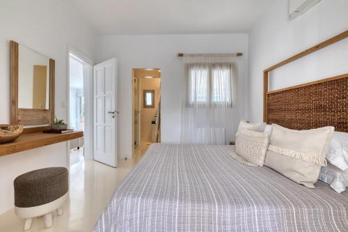 a white bedroom with a large bed and a mirror at Amalgam Homes Paros in Ambelas
