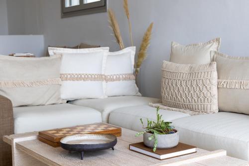 a living room with white couches and a coffee table at Amalgam Homes Paros in Ambelas