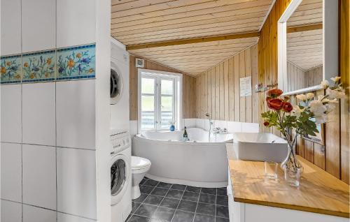 a bathroom with a tub sink and a washing machine at Holiday Home Lyngbakken Fanø Denm in Fanø