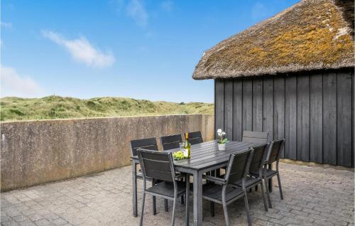 a table and chairs on a patio with a thatch roof at Nice Home In Vejers Strand With Wifi in Vejers Strand