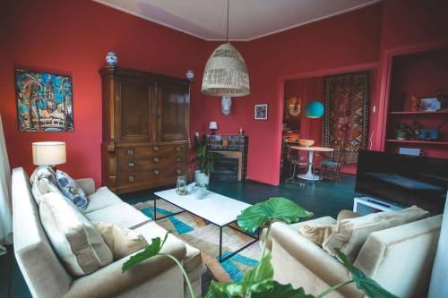 a living room with red walls and two couches at Retreat midden op de Veluwe -ingang Park 1 km in Hoenderloo
