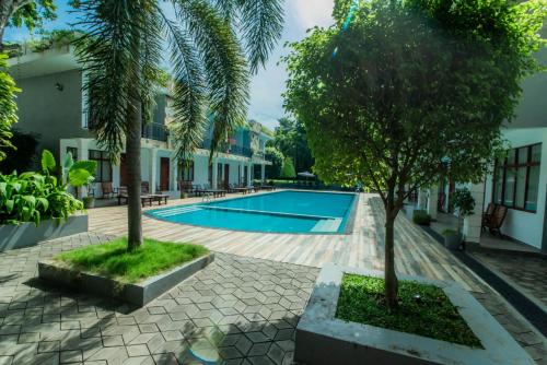 a swimming pool with two trees next to a building at Royal Reach Udawalawe in Udawalawe