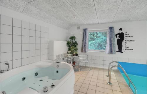 4 Bedroom Cozy Home In Vejers Strand في فايرس ستراند: حمام أبيض مع حوض استحمام ونافذة