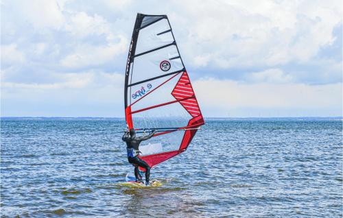 a man standing on a surfboard with a sail on the ocean at Holiday Home Lyngen in Søndervig