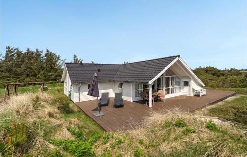 a house with a deck in the middle of a field at Holiday Home Lyngen in Søndervig