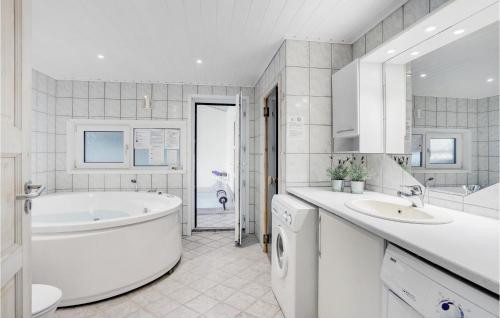 La salle de bains blanche est pourvue d'une baignoire et d'un lavabo. dans l'établissement Awesome Home In Jerup With Indoor Swimming Pool, à Jerup