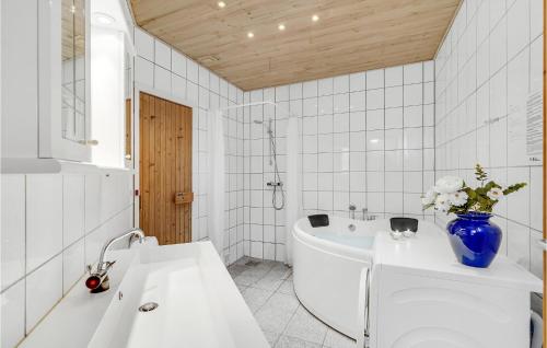 a bathroom with a white tub and a blue vase of flowers at Nice Home In Rm With Wifi in Rømø Kirkeby