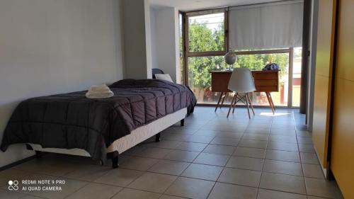 1 dormitorio con cama, escritorio y ventana en Triplex de diseño , amplio , luminoso y céntrico en Carmen de Patagones