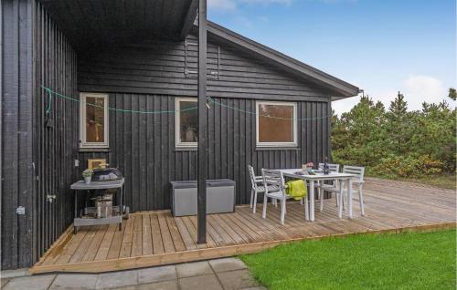 a black house with a table and chairs on a deck at Two-Bedroom Holiday Home In Saby in Sæby